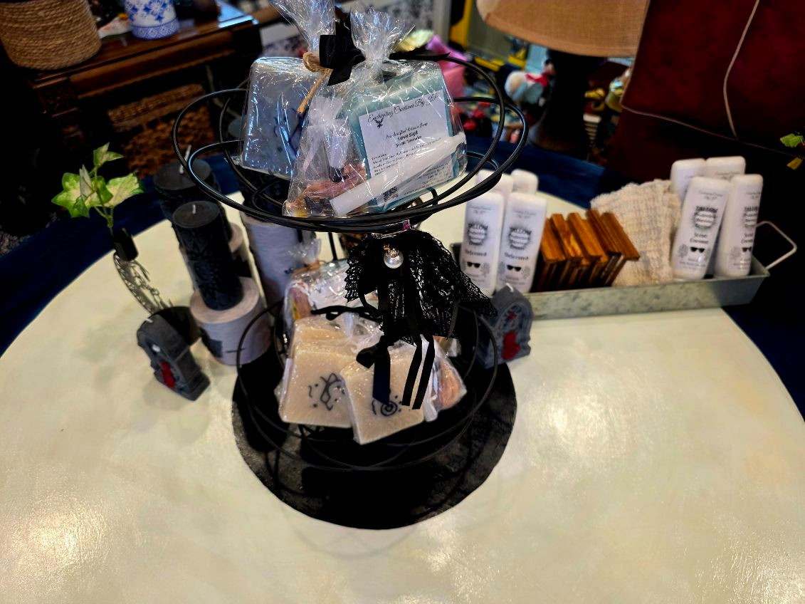 A tiered stand holding wrapped handmade candles and gift soaps