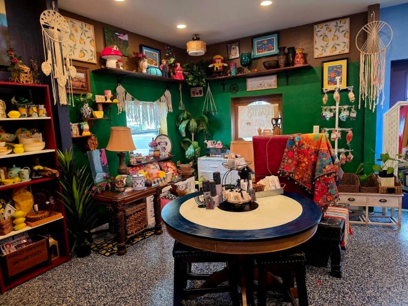 A colorful green room with a round display table and macrame accents