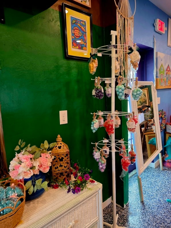 A hanging display rack of handmade soaps against a green wall