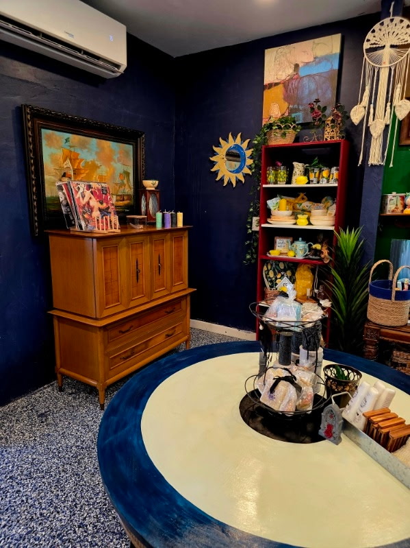 A wide view of the navy blue room with a ship painting and round table