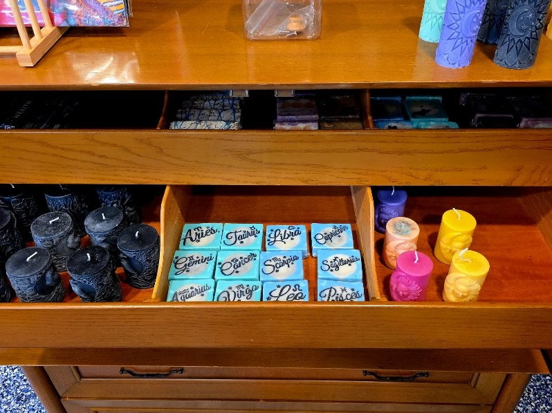 An open drawer of zodiac-themed soap bars and hand-poured candles